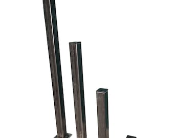 May include: Four black metal square posts of varying heights with a flat base. The posts are arranged in descending order of height from left to right.