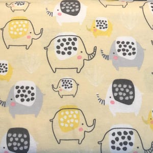 May include: A fabric with a repeating pattern of cartoon elephants in various sizes. The elephants are outlined in black and have gray, white, and yellow bodies with black polka dots. The background is a light yellow.