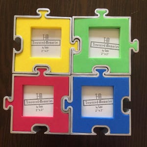 May include: Four colorful puzzle-shaped picture frames in yellow, green, red, and blue. Each frame has a silver border and holds a 2" x 2" photo. The text "Treasured-Memories by Ganz" is printed on each frame.