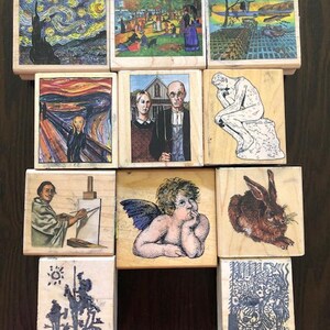 May include: A set of ten wooden stamps featuring famous paintings and sculptures. The stamps are arranged in a grid pattern on a wooden surface. The stamps feature images of The Starry Night, The Scream, American Gothic, The Thinker, and more.