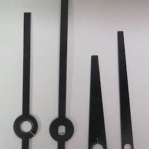 May include: Four black clock hands of different sizes. The hands are made of metal and have a hole in the center for attaching to a clock mechanism.