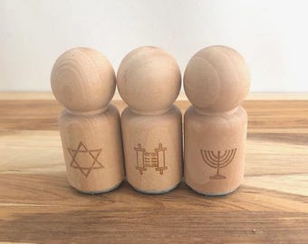 May include: Three wooden stamps with different religious symbols: a Star of David, a Torah scroll, and a menorah.