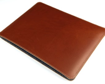May include: A brown leather laptop sleeve with a dark blue lining and white stitching.