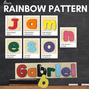 May include: A wooden puzzle with the name "Gabriel" spelled out in colorful letters. The letters are arranged in a rainbow pattern, with each letter corresponding to a different primary color. The letters are red, orange, yellow, green, blue, purple, and pink.