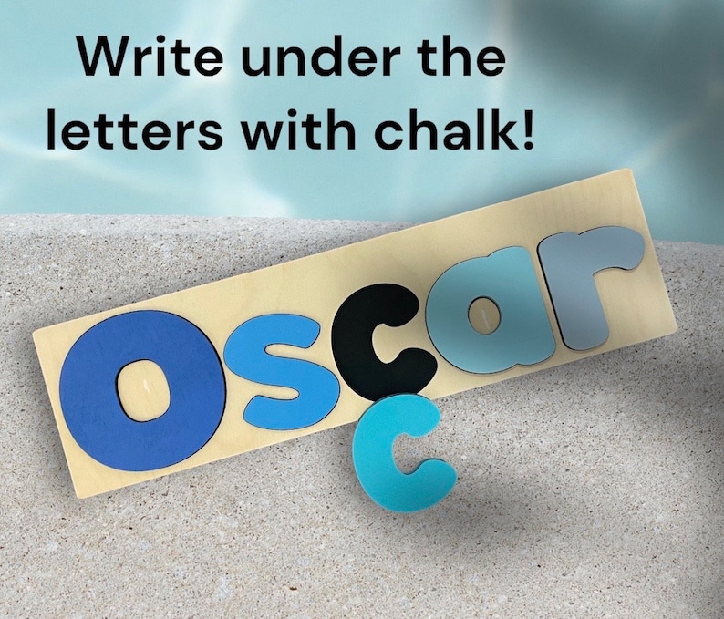 May include: A wooden board with the name "Oscar" spelled out in blue, black, and light blue letters. The letters are raised and have a textured surface. The text "Write under the letters with chalk!" is written above the name.