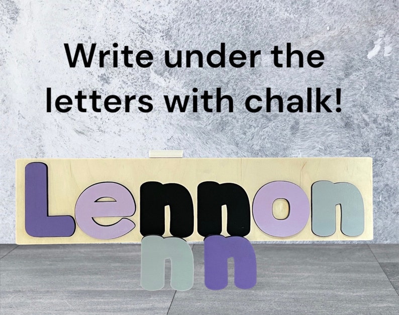 May include: Wooden name puzzle with the name Lennon spelled out in purple, black, and gray letters. The letters are on a light wood background. The text "Write under the letters with chalk!" is above the puzzle.