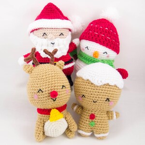 Pode incluir: Um conjunto de quatro enfeites de Natal de croch&ecirc;: um Papai Noel, um boneco de neve, uma rena e um homem de gengibre. Os enfeites s&atilde;o todos sorridentes e t&ecirc;m uma express&atilde;o alegre.