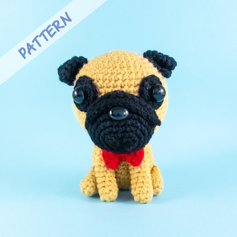 May include: A crocheted pug dog toy with black ears, a black nose, and large black eyes. The pug is wearing a red bow tie and is sitting on a light blue background.