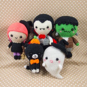Puede incluir: Cinco personajes de Halloween de crochet: un vampir, un fantasma, una bruja, un gato negro y un Frankenstein. Los personajes son todos sonrientes y tienen ojos grandes.