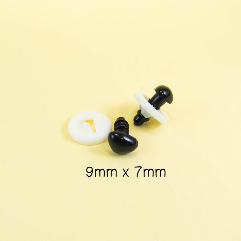Może przedstawiać: Dwa czarne plastikowe oczy bezpieczeństwa z białymi plastikowymi podkładkami. Oczy mają rozmiar 9 mm x 7 mm.
