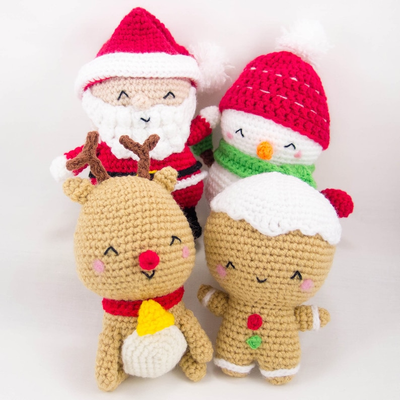 May include: A set of four crocheted Christmas ornaments: a Santa Claus, a snowman, a reindeer, and a gingerbread person. The ornaments are all smiling and have a cheerful expression.