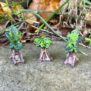 May include: Three miniature fairy garden chairs made of wood and painted brown. Each chair has a green and black leaf on top.