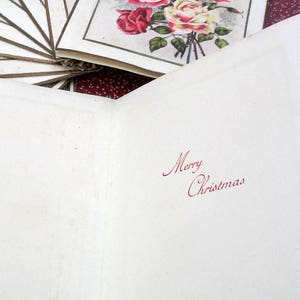 May include: A blank white card with the words "Merry Christmas" written in red ink. The card is folded in half and has a white background.