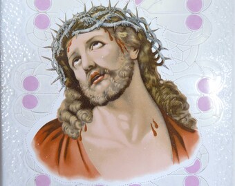 May include: A close-up of a painting depicting Jesus Christ wearing a crown of thorns. His face is pale and he has blood dripping from his forehead. The background is white with a decorative pattern.