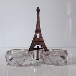 May include: A clear glass salt and pepper shaker set with a metal Eiffel Tower design in the center.