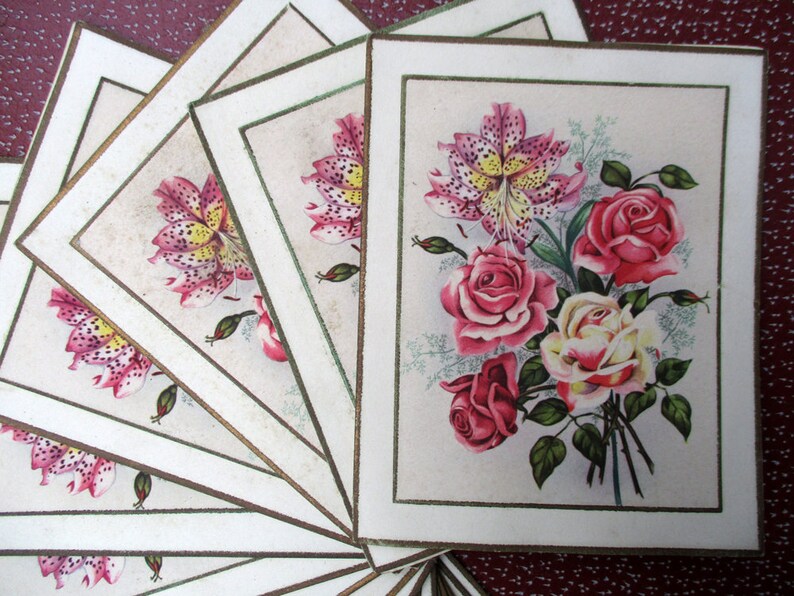 May include: A set of vintage cards with a floral design. The cards feature a bouquet of pink and white roses and lilies with green leaves on a white background.