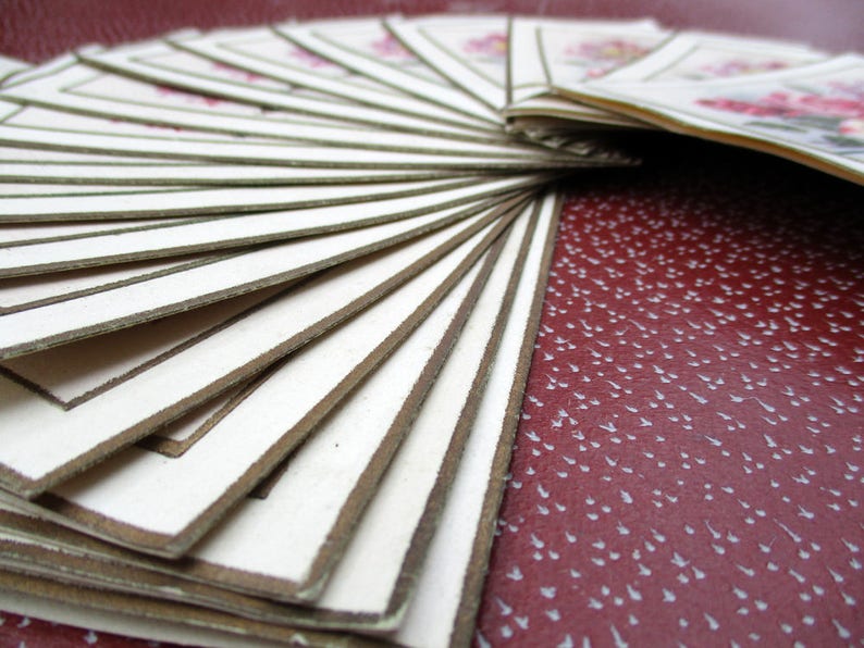 May include: A stack of white cards with brown borders, fanned out in a radial pattern. The cards are arranged in a fan shape, with the top card being the most visible. The cards are all the same size and shape, and they have a simple, elegant design.