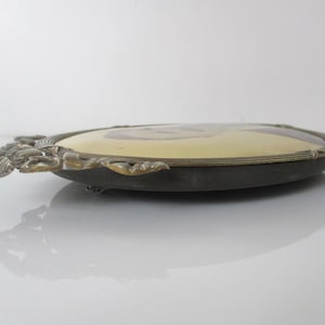 May include: An oval-shaped brass picture frame with ornate details and a gold-toned finish. The frame is designed to hold a portrait photo.