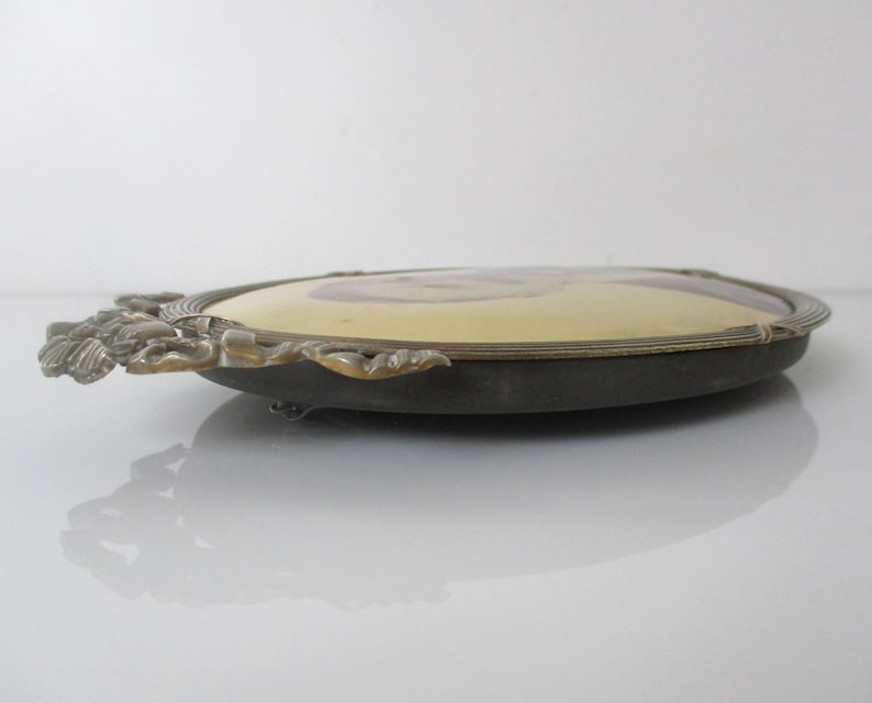May include: An oval-shaped brass picture frame with ornate details and a gold-toned finish. The frame is designed to hold a portrait photo.