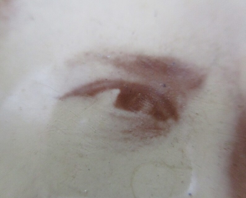 May include: Close-up of a brown eye painted on a white surface. The eye is partially obscured by a white haze.