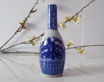 May include: A small blue and white porcelain vase with a floral design. The vase is decorated with a blue and white floral pattern and has a narrow neck.