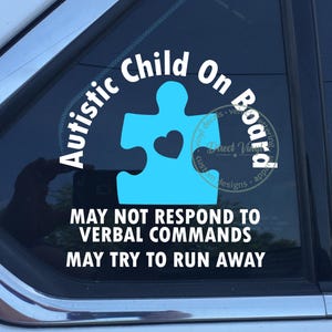 May include: A white and light blue vinyl decal applied to a car window. The design features a light blue puzzle piece with a heart cutout, surrounded by the white text Autistic Child On Board, MAY NOT RESPOND TO VERBAL COMMANDS, MAY TRY TO RUN AWAY.