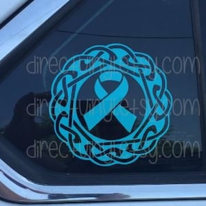 May include: A teal blue ribbon with a Celtic knot design. The ribbon is a symbol of awareness and support for a cause.