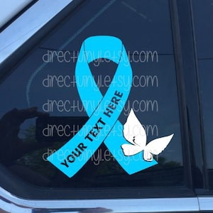 May include: A teal blue ribbon with a white butterfly and the text "YOUR TEXT HERE" on a car window.