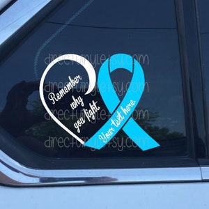 May include: A teal blue ribbon in the shape of a heart with the text "Remember why you fight" and "Your text here" on a black background.