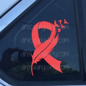 Può includere: Un nastro rosso con un design a forma di piuma e uno stormo di uccelli che volano via. Il nastro è un simbolo di consapevolezza e supporto per una causa.