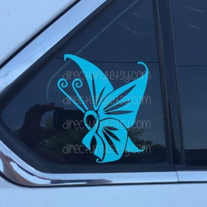 May include: A teal blue butterfly decal with intricate details, applied to the back window of a car.