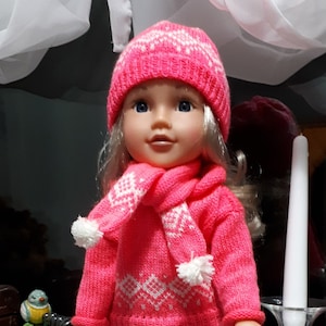May include: A pink knitted doll with blonde hair wearing a pink and white patterned sweater, matching hat and scarf, blue jeans, and pink and white striped leg warmers with white fur trim. The doll is wearing black boots with brown soles.