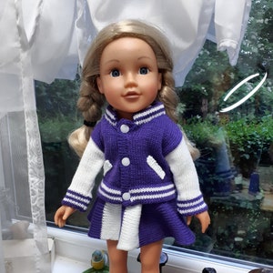 May include: A doll wearing a purple and white varsity jacket and skirt. The doll has blonde hair and blue eyes. She is wearing blue sneakers.