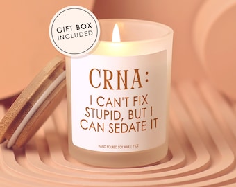 May include: A lit soy wax candle in a frosted glass jar with a wooden lid. The label reads "CRNA: I CAN'T FIX STUPID, BUT I CAN SEDATE IT." The candle is 7 oz and comes in a gift box.