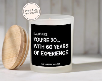 May include: A white frosted glass candle with a black label that reads "Smells Like You're 20... With 60 Years of Experience." The candle has a wooden lid and is labeled "Hand Poured Soy Wax | 7 oz." A circular sticker reads "Gift Box Included."