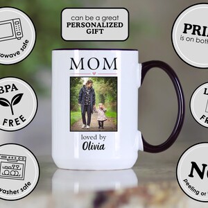 May include: White ceramic mug with a black handle and rim. The mug features the word "MOM" above a photo of a person and child, with "loved by Olivia" below. The mug is microwave and dishwasher safe, BPA and lead free, and the print is on both sides.