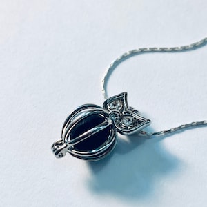 May include: A silver owl charm necklace with a clear crystal cage pendant. The owl has clear crystal eyes and a silver chain.