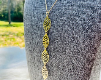 Könnte beinhalten: Eine goldene Halskette mit einem Anhänger aus fünf filigranen, miteinander verbundenen Blattformen.