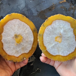 May include: A set of three ceramic mugs with a speckled, matte finish. The mugs are in shades of cream, light gray, and dark gray. Each mug has a simple, minimalist design and a rounded handle.