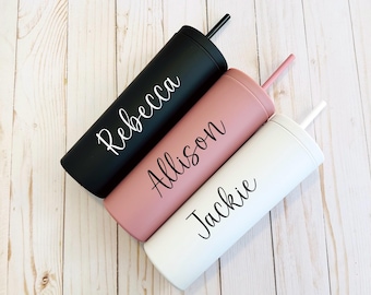May include: Three cylindrical tumblers with matching straws, each featuring a matte finish and a personalized name in script font. The black tumbler is labeled Rebecca, the dusty rose tumbler is labeled Allison, and the white tumbler is labeled Jackie.