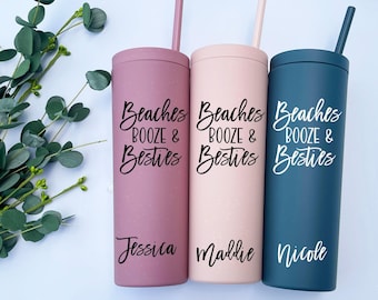 May include: Three tall, cylindrical tumblers with matching straws in dusty rose, light pink, and dark blue. Each tumbler features a speckled finish and the black text "Beaches BOOZE & Besties" followed by a personalized name: Jessica, Maddie, or Nicole.