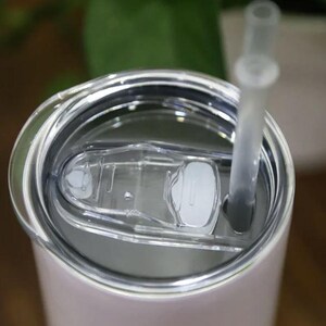 A close-up view of a clear plastic lid on a white container, with a straw sticking out of it.
