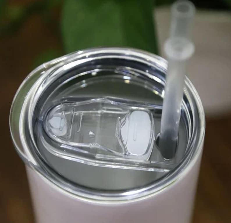 A close-up view of a clear plastic lid on a white container, with a straw sticking out of it.