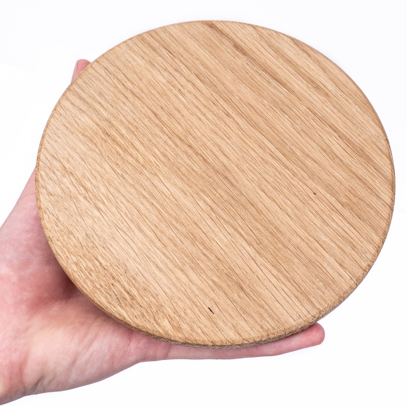 Puede incluir: Una tabla de cortar redonda de madera con un acabado de grano de madera natural.