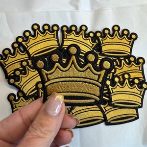 Pode incluir: Patches de coroa bordados a ouro com borda preta. As coroas apresentam um design detalhado e estão empilhadas. Estes patches são adequados para roupas, acessórios ou projetos de artesanato.