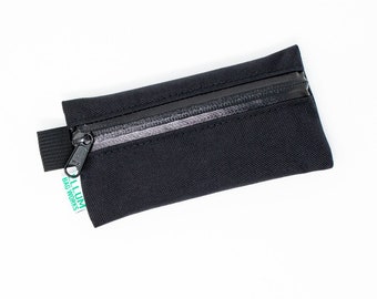 May include: A black zippered pouch with a green label that reads "LLUMI BAG WORKS".