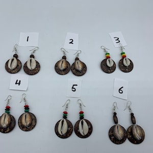 May include: Six pairs of earrings with a cowrie shell and a wooden circle. The earrings are numbered 1 through 6.