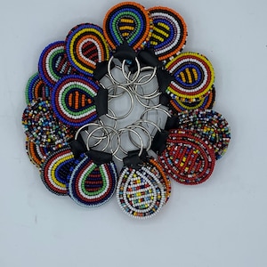 May include: A set of colorful beaded keychains in the shape of teardrops. Each keychain features a different pattern of red, blue, yellow, green, and white beads.