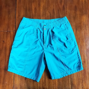 May include: Teal blue shorts with an elastic waistband and a button closure.