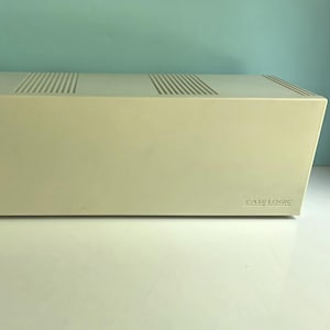 May include: A rectangular, off-white plastic storage case for media with a smooth front surface and two sets of vertical ventilation slats on the top panel. The brand name CASE LOGIC is embossed in small, capital letters on the bottom right corner.